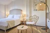 Collectief onderzoek © Villa Giada spEace & Bike Resort Lichte slaapkamer met comfortabel bed, rotan stoel en warme verlichting