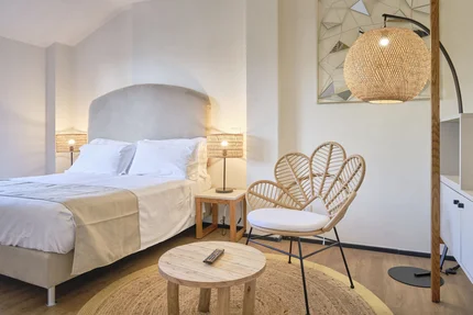 Lichte slaapkamer met comfortabel bed, rotan stoel en warme verlichting