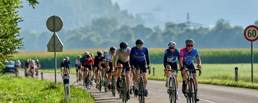Der Kufsteinerland Radmarathon © Kufsteinerland / Martin Bihounek Radfahrer in einer Gruppe auf einer Landstraße bei Bergkulisse