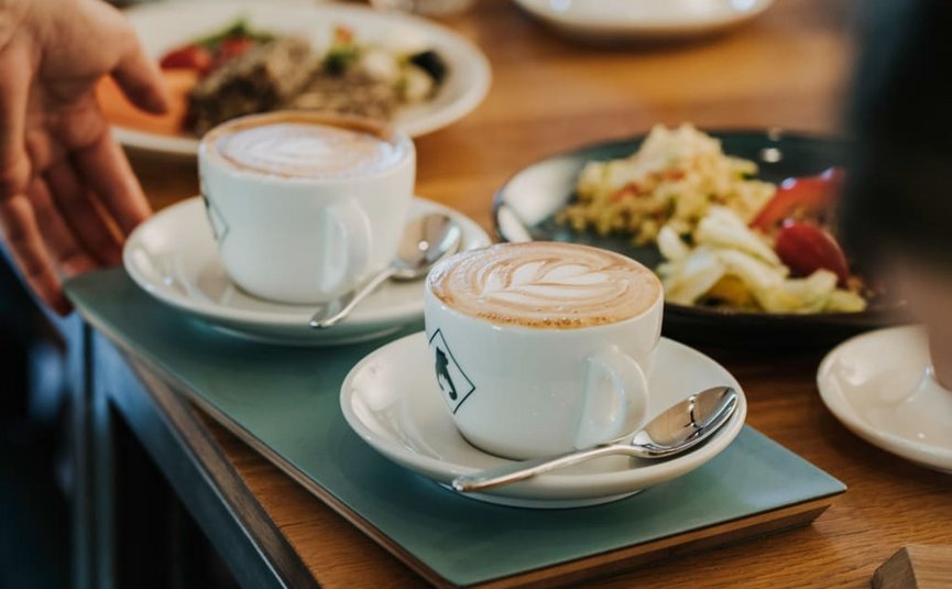 Two cups of cappuccino with latte art on a tray on a table
