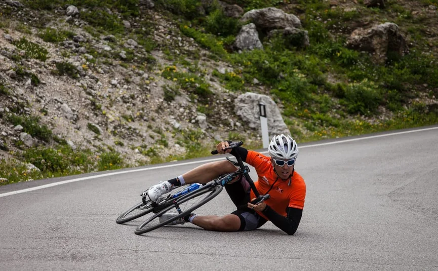 Performance Weeks - 4 nights Fietser in oranje shirt gevallen op asfaltweg bij bocht