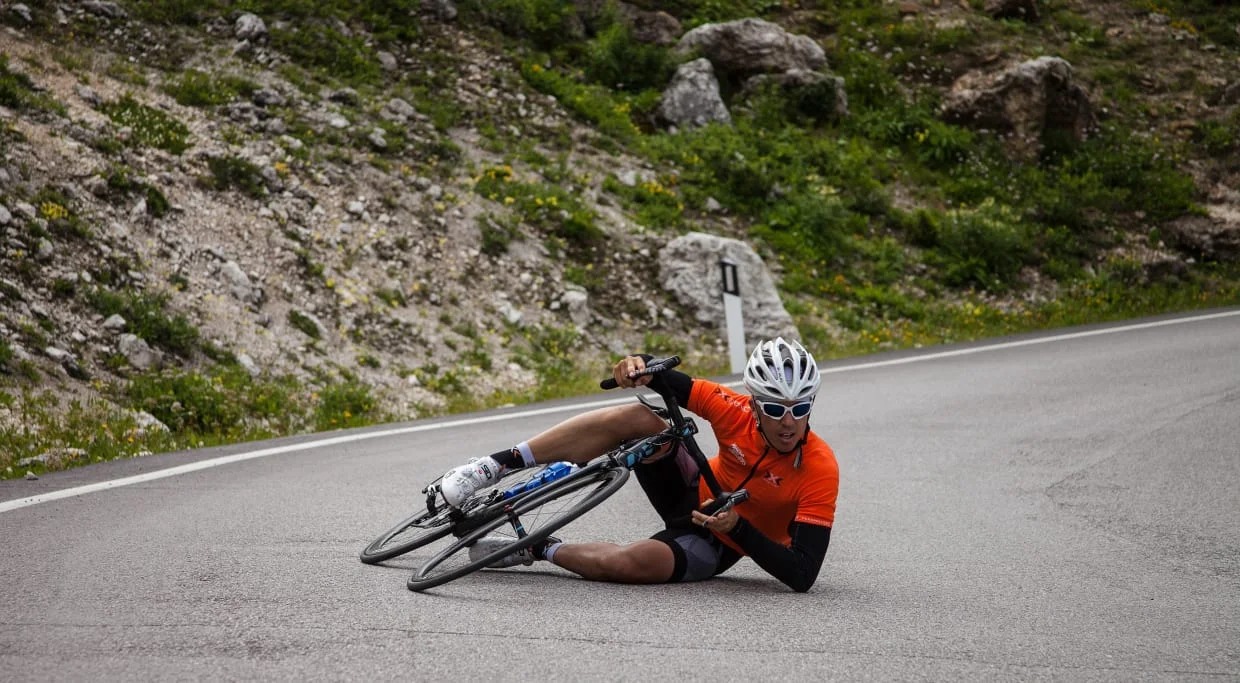 Performance Weeks - 4 nights Fietser in oranje shirt gevallen op asfaltweg bij bocht