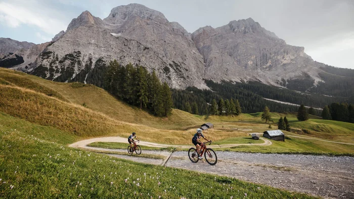 Due ciclisti su un sentiero di montagna con le Alpi sullo sfondo