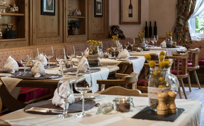 Rustikal eingedeckte Restauranttische mit Holzstühlen und Blumendekoration