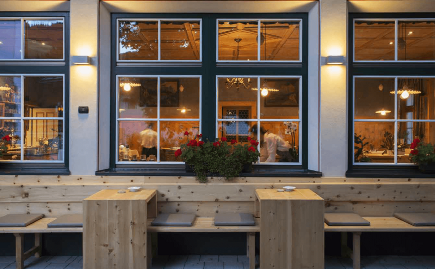 Blick auf eine gemütliche Außenterrasse eines Restaurants mit Holzsitzplätzen