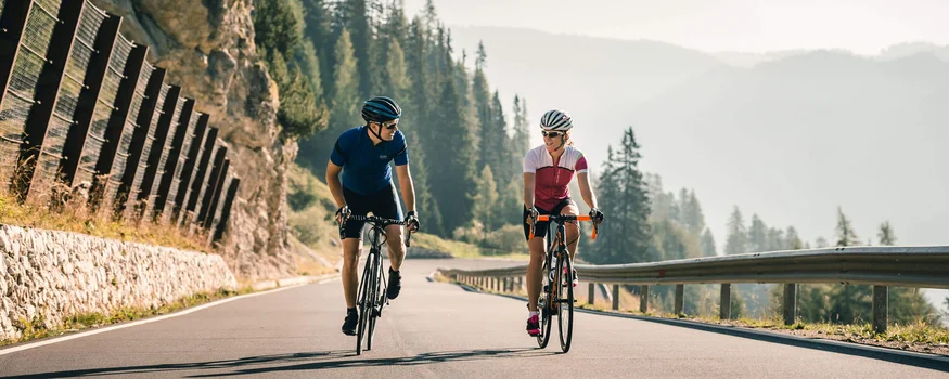 Warum Alta Badia auf jede Roadbike-Bucket-List gehört © Molography Zwei Radfahrer fahren bergauf auf einer Straße in den Bergen