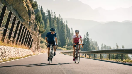 Warum Alta Badia auf jede Roadbike-Bucket-List gehört © Molography Zwei Radfahrer fahren bergauf auf einer Straße in den Bergen