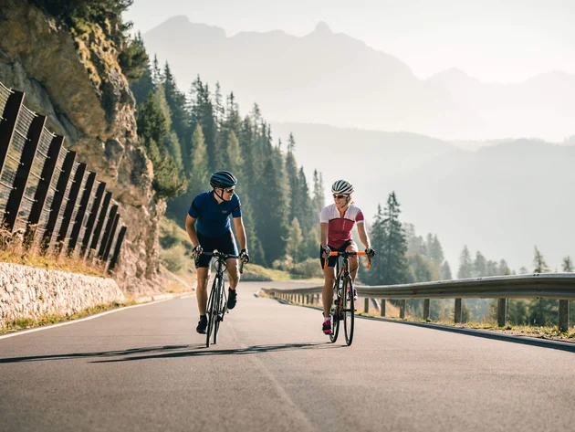 Warum Alta Badia auf jede Roadbike-Bucket-List gehört © Molography Zwei Radfahrer fahren bergauf auf einer Straße in den Bergen
