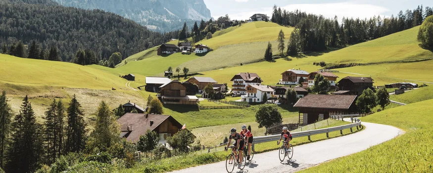 Goldene Kilometer: Rennrad-Herbst in San Vigilio © Alex Moling Radfahrer auf Landstraße mit Berg und Dorf im Hintergrund