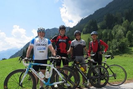 Quattro ciclisti con biciclette da corsa davanti a montagne e valle verde