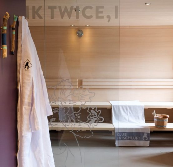 Moderne sauna met houten bank, handdoek en badjas aan de muur