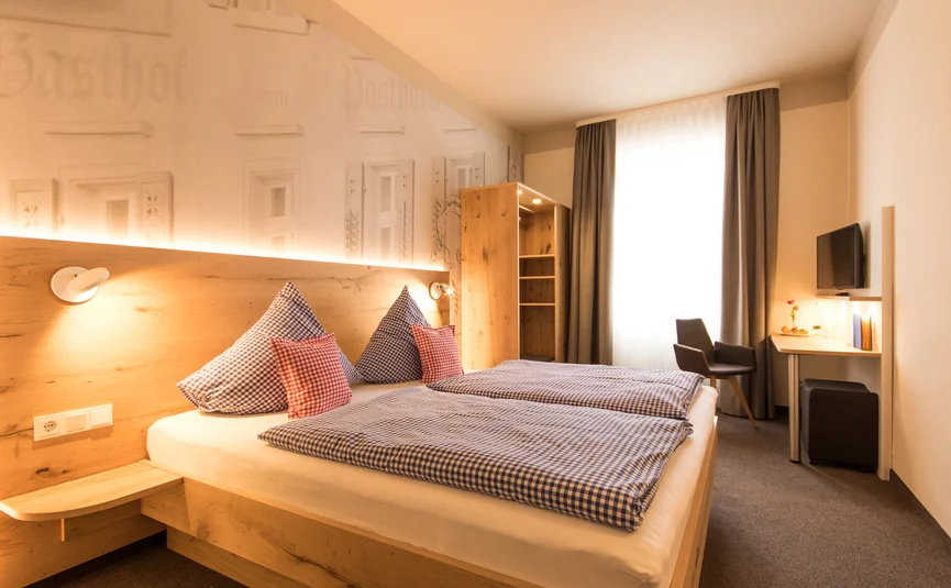 Posthorn Hotel-Ristorante Camera d’albergo luminosa con due letti, arredi in legno, una grande finestra e una scrivania