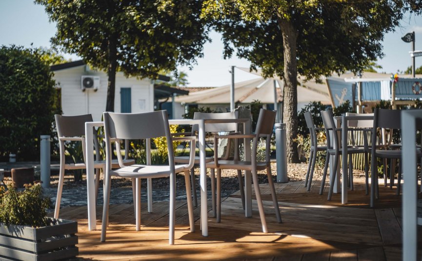 Sedie e tavoli vuoti su un patio in legno all'aperto sotto gli alberi