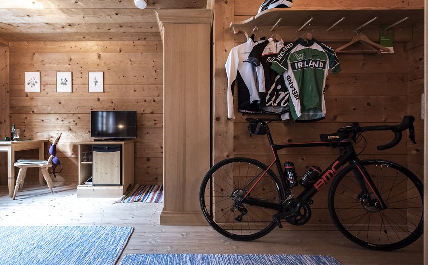 Fahrrad mit Radtrikots und Helm in Zimmer mit Holzwänden