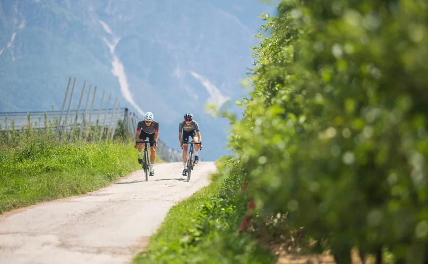 Rennrad Urlaub in am Levico See © Heiko Mandl Zwei Radfahrer fahren auf einem ländlichen Weg mit Bergen im Hintergrund