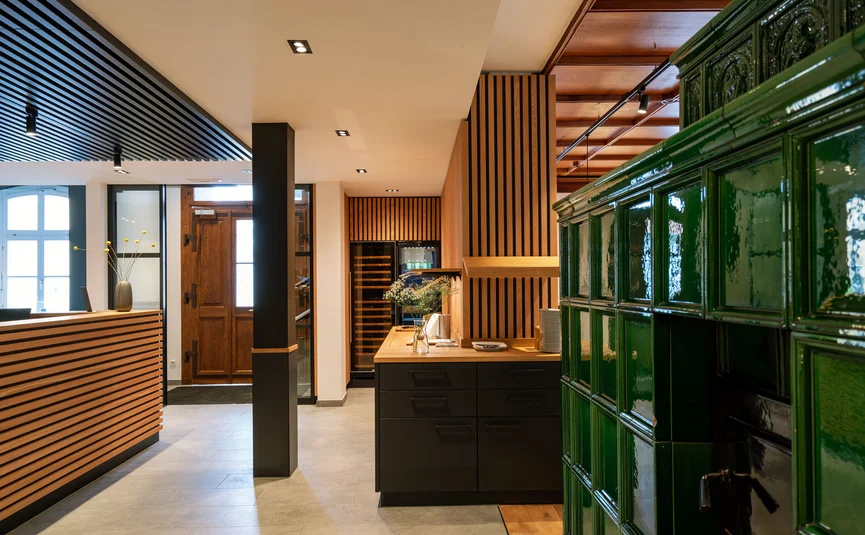 Posthorn Hotel-Ristorante Interno luminoso con stufa piastrellata verde, listelli in legno e bancone
