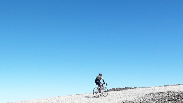 Circumnavigazione della Sierra Nevada © quäldich.de GmbH Un ciclista pedala su un sentiero innevato sotto un cielo azzurro limpido