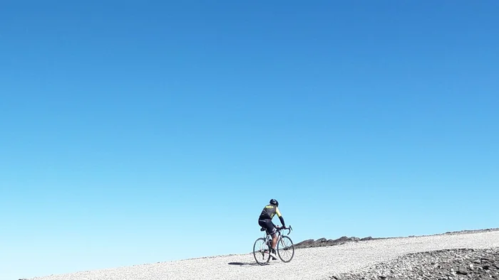 Ein Radfahrer fährt auf einem schneebedeckten Weg unter klarem blauem Himmel