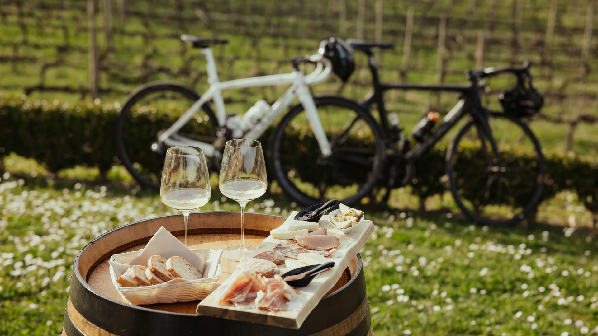 Vino bianco, pane e affettati su botte con biciclette sullo sfondo