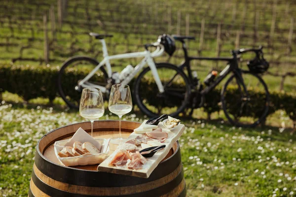 Aanbiedingen © Alex Moling Witte wijn, brood en vleeswaren op wijnvat met fietsen op de achtergrond