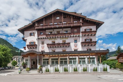 Large Hotel Union with balconies in front of mountain scenery and blue sky
