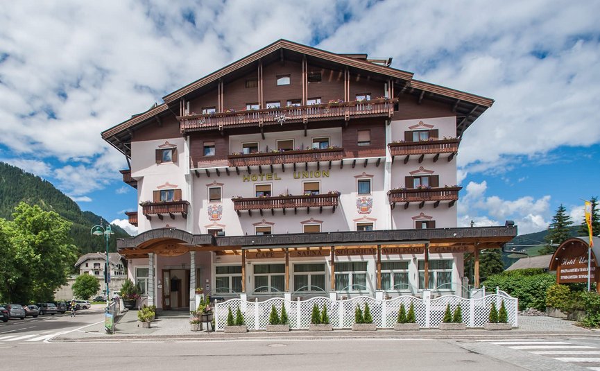 Großes Hotel Union mit Balkonen vor Berglandschaft und blauem Himmel