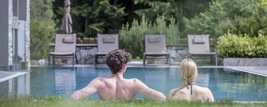Mehr als Rennradurlaub: Sporthotel Zoll setzt auf Performance © Fabian Schaiter Paar entspannt im Pool mit Liegestühlen und Sonnenschirm im Hintergrund