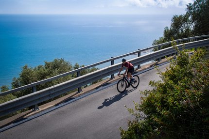 Radfahrer fährt eine Küstenstraße mit Blick auf das Meer entlang