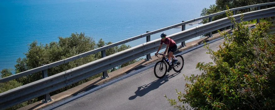 Saisonstart am Meer © Valentina Morri Italy Radfahrer fährt eine Küstenstraße mit Blick auf das Meer entlang