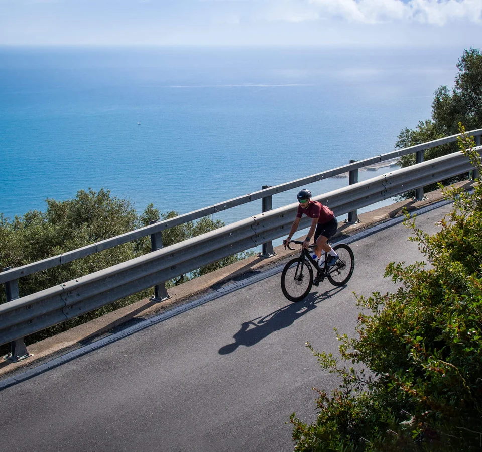 Rennradfrühling an der Ligurischen Riviera © Valentina Morri Italy Radfahrer fährt eine Küstenstraße mit Blick auf das Meer entlang