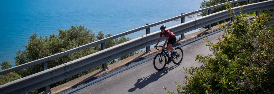 Radfahrer fährt eine Küstenstraße mit Blick auf das Meer entlang