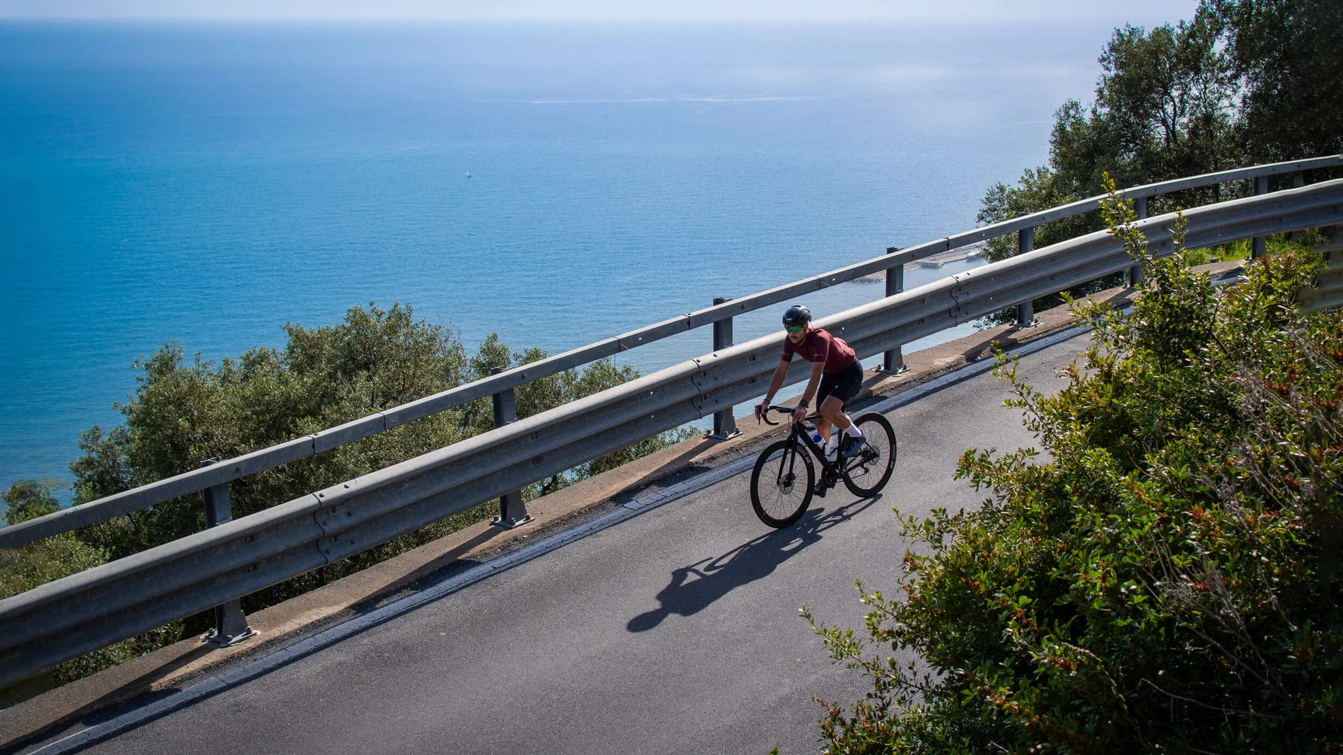 Cyclist riding along coastal road overlooking the sea