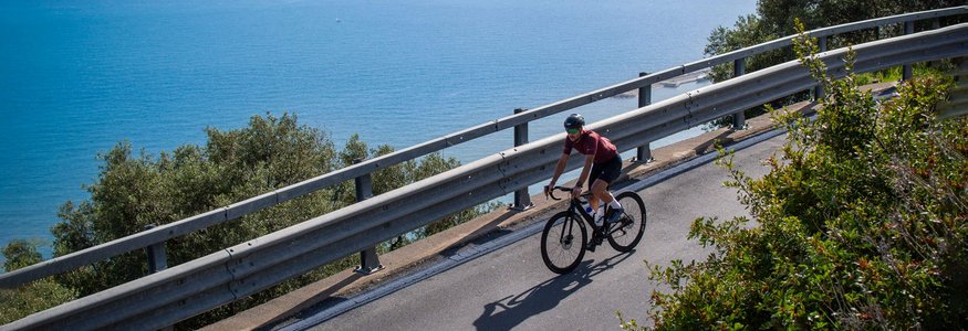 Cyclist riding along coastal road overlooking the sea