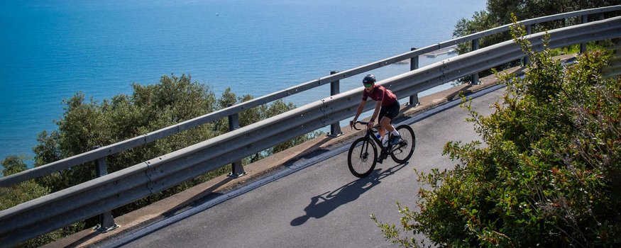 Saisonstart am Meer © Valentina Morri Italy Radfahrer fährt eine Küstenstraße mit Blick auf das Meer entlang