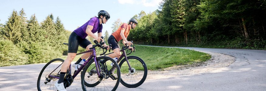 Due ciclisti che pedalano su una strada in una foresta montana.