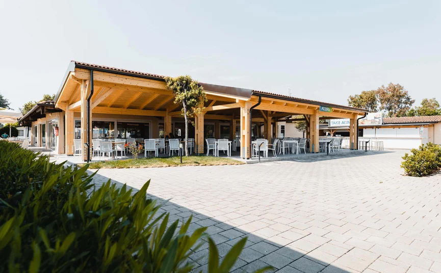 Leeres Außenrestaurants mit Holzdach und weißen Stühlen an sonnigem Tag