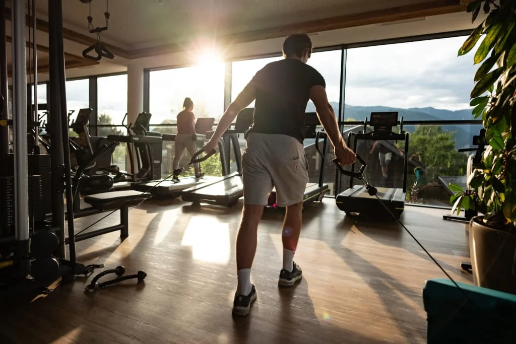 Persoon traint met kabelapparaat in sportschool met zonlicht en bergzicht