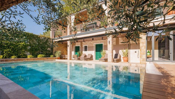 Moderner Pool mit Liegestühlen und grünen Türen an Haus