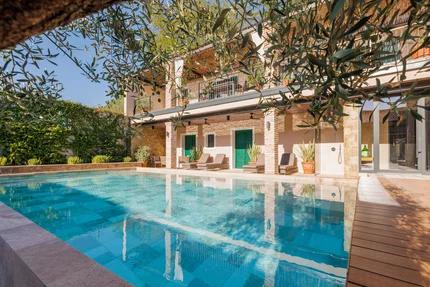 Modern zwembad met ligstoelen en groene deuren aan huis