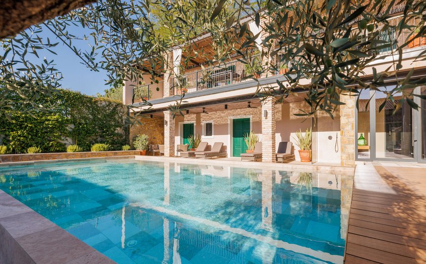 Modern pool with loungers and green doors on house
