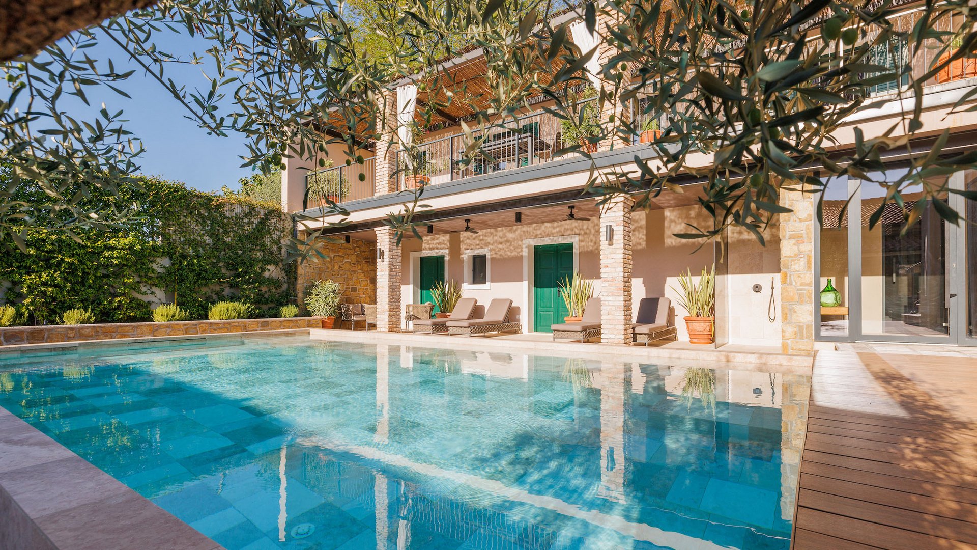 Moderner Pool mit Liegestühlen und grünen Türen an Haus