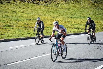 Tre ciclisti su strada, uno fa pollice in su