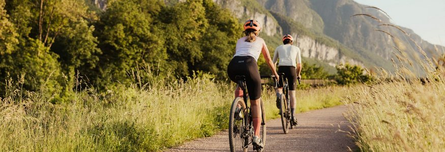 Zwei Radfahrer fahren auf einem Weg mit Bergen im Hintergrund