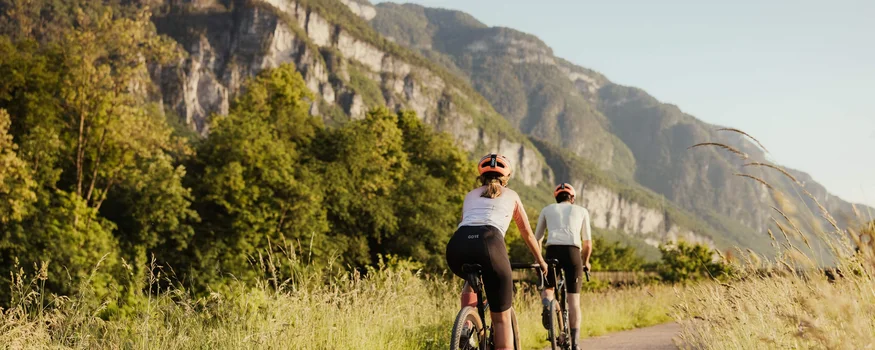Two cyclists riding on a path with mountains in the background