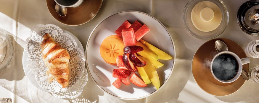 Bike & Kulinarik: Vom Gipfel in den Gourmethimmel © Rudi Wyhlidal Frühstückstisch mit Croissant, Obstplatte und Kaffee bei Tageslicht