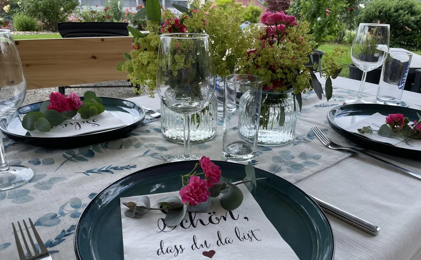 elegantly set outdoor table with flowers and napkins with writing