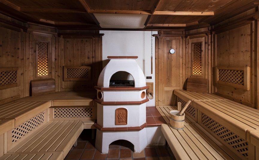 Sauna with wooden benches and a white stove in the center