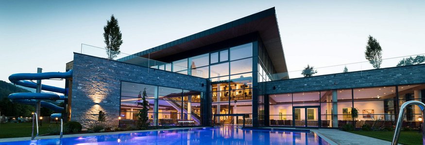 Modern building with illuminated pool and water slide at dusk