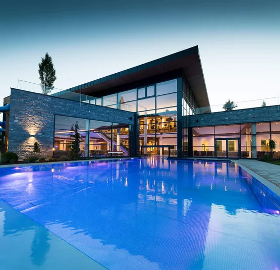 Edificio moderno con piscina illuminata e scivolo d'acqua al crepuscolo