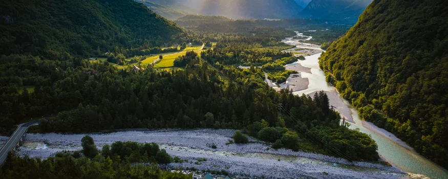 Raggi di sole su una valle fluviale e montagne al tramonto